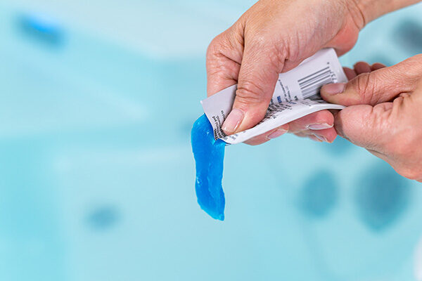 2 hands squeezing FROG Hot Tub Pipe & Jet Cleanser Packets - into a hot tub